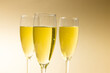 Close-up of champagne flutes with champagne against beige background, copy space