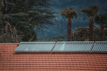 Water solar collector on a red metal roof. Solar thermal and solar panel for hot water.