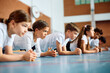© Drazen - Group of schoolkids exercising during PE class at school gym.