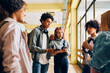 © Drazen - Multiracial group of teenage friends talk in hallway at high school.
