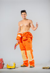 Wall Mural - Topless professional firefighter stands exuding confidence as he holds an iron axe in one hand while extending his other hand in a thumbs up gesture accompanied by a warm smile.