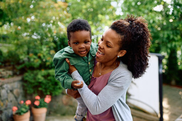 Wall Mural - Playful black mother with her son in backyard.