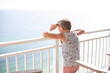 © Cavan Images - Person looking over balcony at beach resort on sunny day