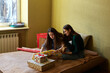 © Cavan Images - two young women with New Year's gift wrapping at home on the bed