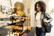 © Cavan Images - Woman looking in a bakery window from outside.