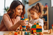 © VisualProduction - Child development specialist looking at little girl playing with toys in playroom. Generative AI