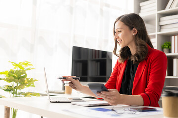 Successful businesswoman using laptop and computer while making paperwork for financial mathematics analytical research concept