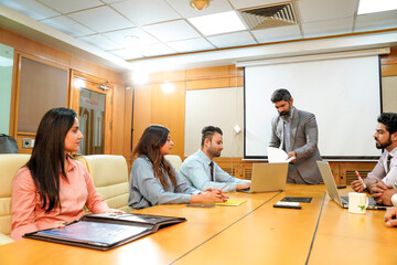 Wall Mural - Indian ceo presenting project information to other businesspeople, using laptop and white board.