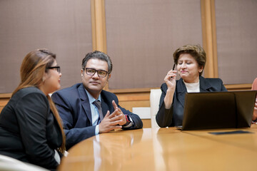 Wall Mural - Indian corporate woman presenting project information to other businesspeople or employee, using laptop at meeting hall.