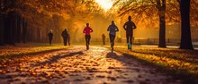 A Group Of Runners Running At Sunrise In The Park During Autumn. Generative AI.