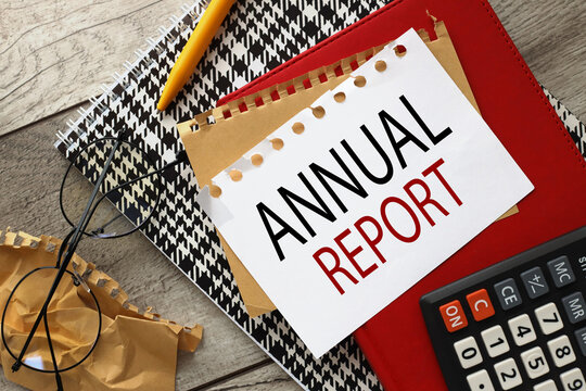 Annual Report wooden background with sheets of paper on a red notepad. word on page