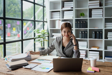 Consultant, Asian businesswoman working on the phone who discussion financial work and marketing business plan to increase company profits, ready to use computer and marketing planning documents