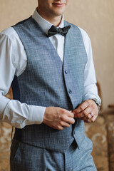 Wall Mural - Morning of the groom and details, white shirt, blue vest, good light, young man, stylish groom getting dressed, getting ready for the wedding ceremony. close-up of male hands