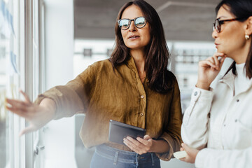 Poster - Mature business woman brainstorming with her colleague in an office