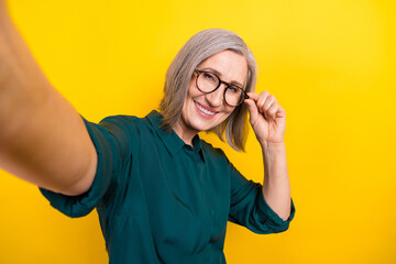 Sticker - Portrait of cheerful aged lady arm touch eyeglasses make selfie toothy smile isolated on yellow color background