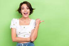 Photo Of Cute Impressed Lady Wear White Blouse Open Mouth Pointing Thumb Empty Space Isolated Green Color Background