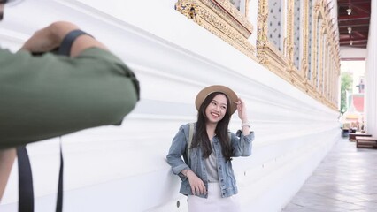 Wall Mural - Portrait of Asian man and woman couple travelers in relationship. Boyfriend taking a photo of girlfriend in temple on street in Bangkok, Thailand, Southeast Asia - people traveling photography concept