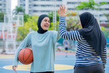 Young Asian Muslim Girl Teen Wearing Hijab Going To Play Basketball On The Outdoor Court In The Morning With Determination, Muslim Sport Concept.