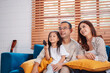 © Kiattisak - Asian family consisting of happy parents and daughter watching TV or movie together on sofa in living room at home. enjoy relaxing happiness