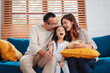 © Kiattisak - Asian Family consisting of parents, happy daughter watching TV or movie eating popcorn on sofa in living room at home. enjoy relaxing happiness.