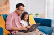 © Kiattisak - Cute little asian daughter with father working on laptop at home. single loving dad man shopping insurance to daughter by online technology.