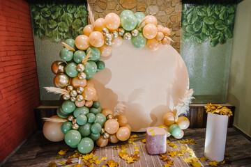 reception at birthday party. arch decorated green, brown, golden balloons, dry autumn leaves for wed