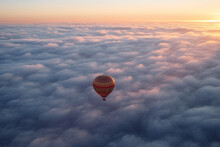 Generative AI Illustration Of Red Hot Air Balloon Flying Over Fluffy Clouds Against Orange Sundown Sky In Evening Time