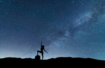 Wall Mural - woman silhouette dancing in the night, on the bright milky way galaxy background.