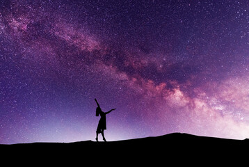 Wall Mural - Woman silhouette dancing in the night, on the bright Milky Way Galaxy background.