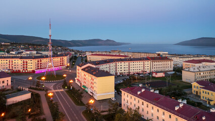 Wall Mural - Aerial view of the city of Magadan. Top view of the streets, buildings and TV tower. In the distance is Nagaev bay and mountains. Morning cityscape at dawn. Magadan region, Far East of Russia.