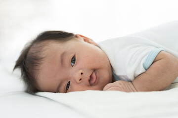 Newborn baby sleeping on blanket on white bed. Infant lying on white bed. Asian newborn baby sleeping in prone position. Asian infant