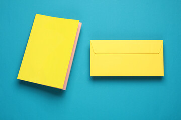 Wall Mural - Notepad with a yellow cover and envelope floating on blue background