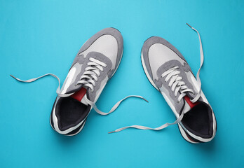 Sticker - Sneakers with untied laces on a blue background. Top view