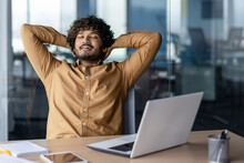 Task Successfully Completed And Job Well Done, Businessman Typing Away Inside Office At Workplace, Satisfied Hispanic Man With Hands Behind Head Dreaming And Smiling With Closed Eyes.