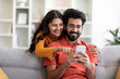 © Prostock-studio - Mobile Gaming. Cheerful Indian Couple Playing Online Games On Smartphone At Home