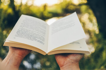 Wall Mural - Open book on a sunset background. Reading, studying, school. Read a book outdoors