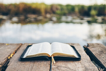 Open Bible on a wooden board near the river