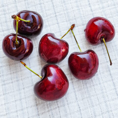 Wall Mural - Several ripe cherries on a white linen tablecloth. Summer berries on a white background.