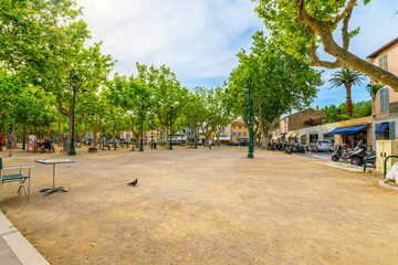 The spacious tree lined Place des Lices town square and park in the historic center of Saint-Tropez, France, along the Cote d'Azur French Riviera.	