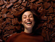© Mauricio - Portrait of a happy laughing young woman laying on top of a pile of delicious chocolate bars.