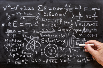 Mano humana señalando operaciones y formulas de física cuántica escritas con una tiza en la pizarra