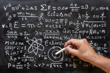 Mano humana señalando operaciones y formulas de física cuántica escritas con una tiza en la pizarra