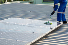 Man Using A Mop And Water To Clean The Solar Panels That Are Dirty With Dust And Birds' Droppings To Improve The Efficiency Of Solar Energy Storage.