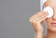 © Acronym - Young woman cleaning her face with a cotton pads. Girl removing cosmetics with hygienic discs.