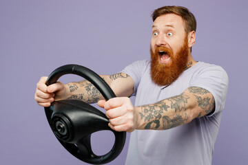 Side view young surprised fun redhead bearded man wear violet t-shirt casual clothes hold steering wheel driving car isolated on plain pastel light purple background studio portrait Lifestyle concept