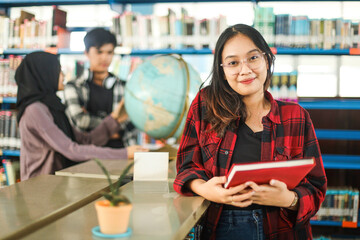 happy asian student girl visiting public library for work on study research project, holding noteboo