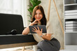 © Prathankarnpap - Determined millennial asian woman sitting on floor in living room and using digital tablet. People, technology and lifestyle concept