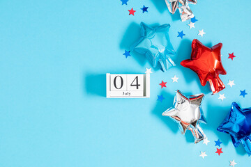 Wall Mural - 4th of July, USA Presidents Day, Independence Day. Flat lay top view of  celebration decor: wooden calendar, inflatable star balloons twinkling confetti on blue background with space, promotion or gre