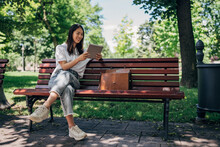 Young Japanesse Woman Using Digital Tablet While Resting In The Park