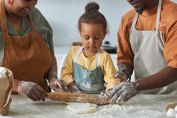 Wall Mural - African American little girl helping her parents to rolling the dough with rolling pin